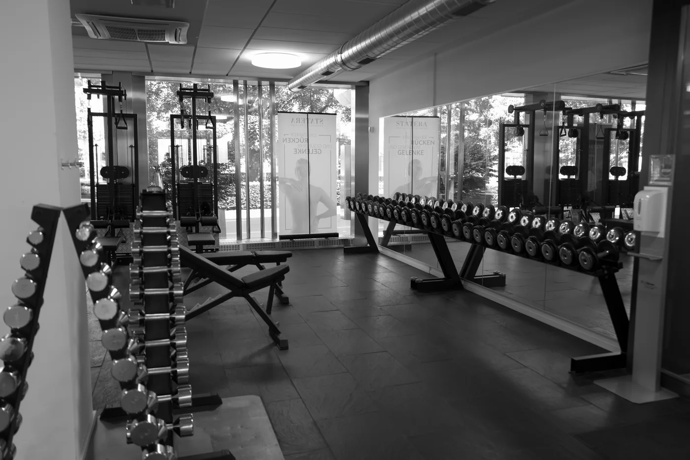 Gesamtansicht des STATERA-Studios mit Trainingsgeräten und Hantelablage